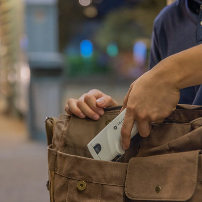 Person placing TASER Bolt 2 stun gun into a brown messenger bag for easy carry