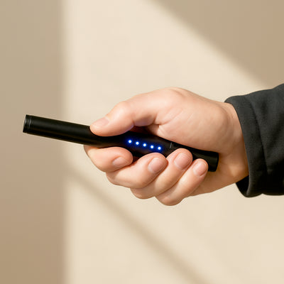 Hand holding a rechargeable black stun pen with blue LED power indicators